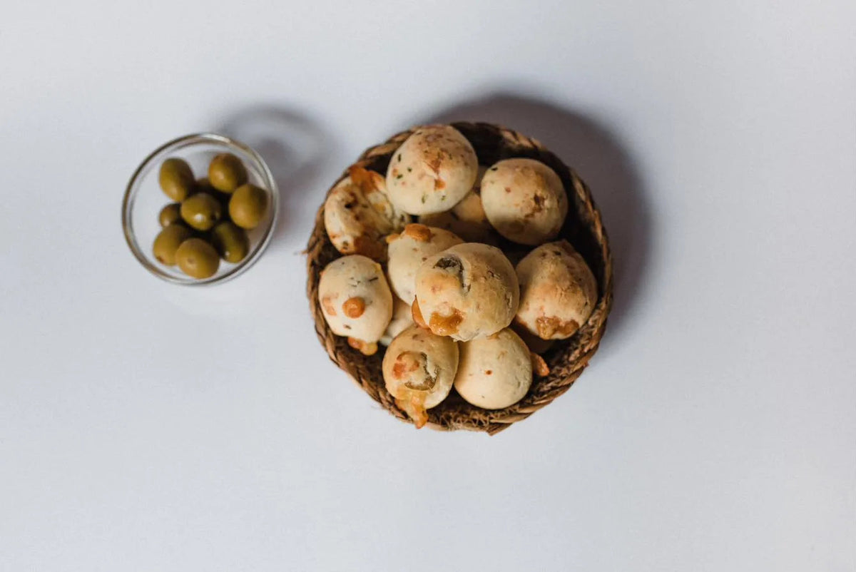 Canasta de chipás de olivas junto a un cuenco con aceitunas verdes